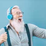 Starszy człowiek z brodą i tatuażem i błękitnymi słuchawkami na uszach