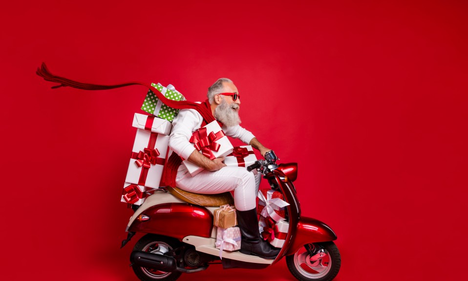 Nowoczesny święty Mikołaj z prezentami na skuterze
